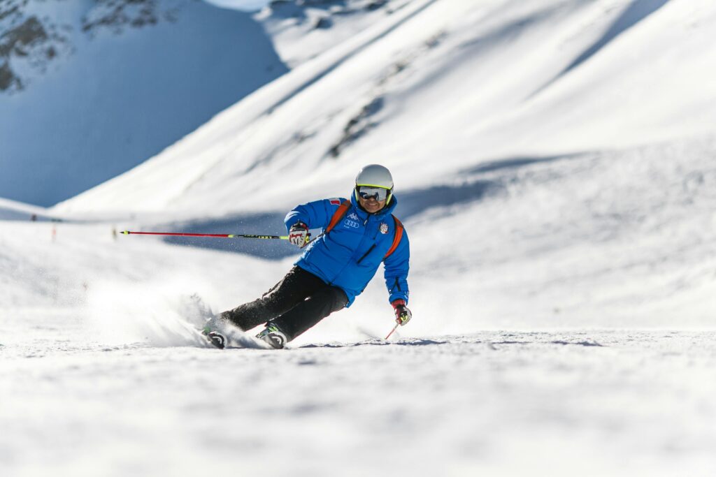 Dynamic action shot of a skier in bright blue attire making a sharp turn on the snowy slopes of Mount Washington Alpine Resort